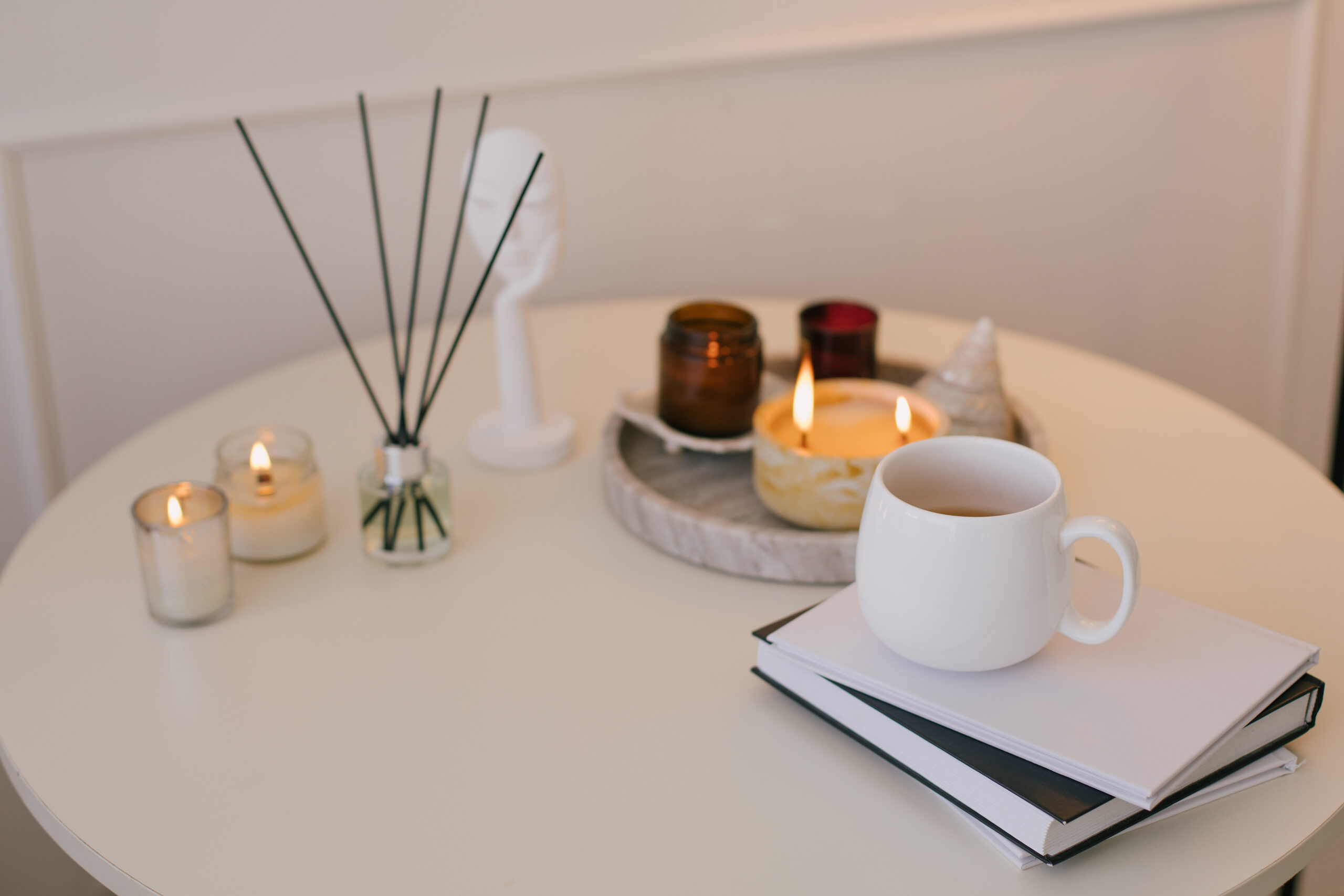 Still life with white mug, aromatic sticks and candles on a table in a cozy living room.
